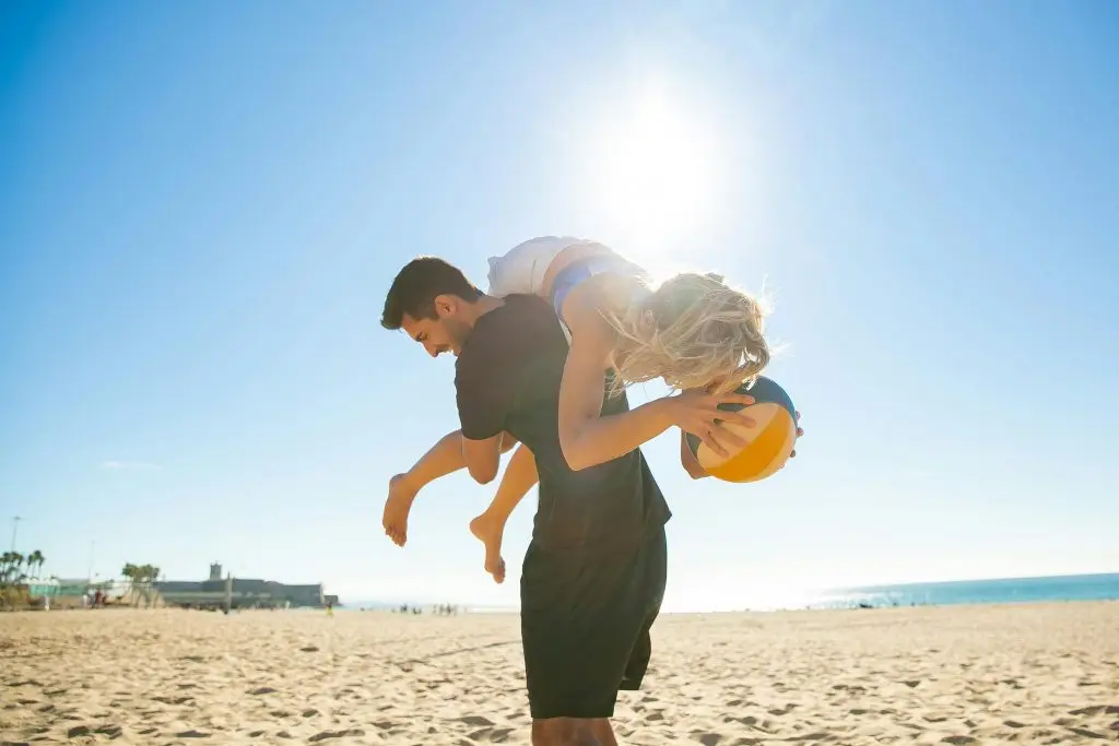 Couple playing on the beach with a volleyball, symbolizing fun, balance, and enjoying life in retirement.