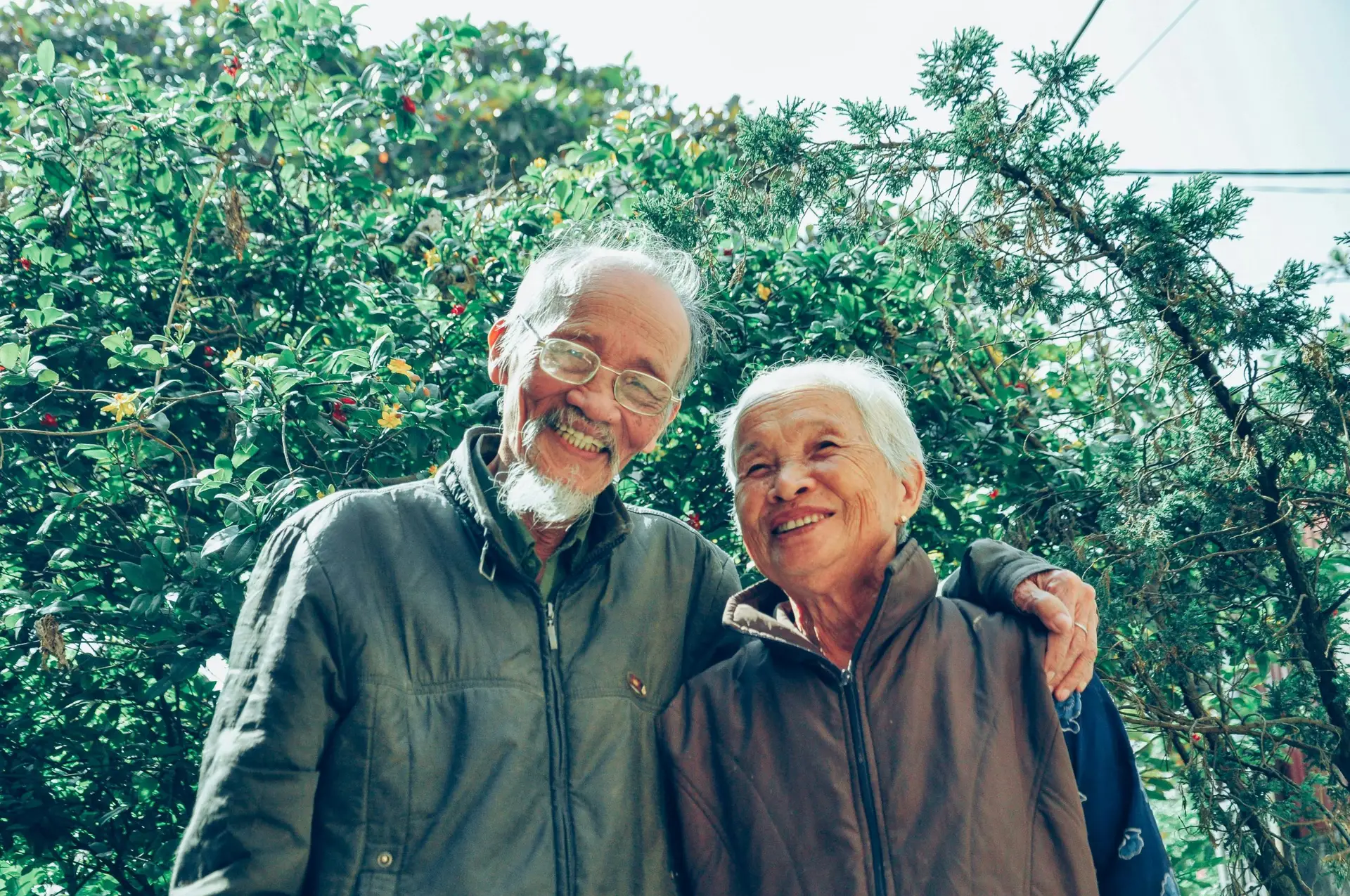 Smiling older couple hugging outdoors representing health and happiness in retirement.